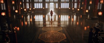 Movie still from “Mulan” (2020), directed by Niki Caro – A woman in a red coat walking down a hall way; Extreme Wide shot, High angle