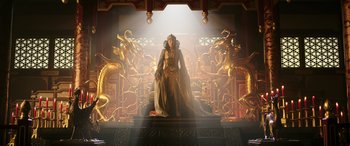 Movie still from “Mulan” (2020), directed by Niki Caro – A woman dressed as a queen standing on a throne in front of a golden dragon statue; Wide shot, Low angle