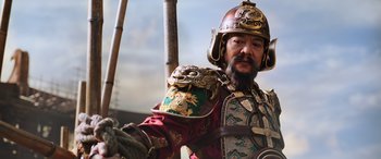 Movie still from “Mulan” (2020), directed by Niki Caro – A man wearing a helmet and holding a sword; Close Up shot, Low angle