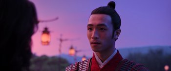 Movie still from “Mulan” (2020), directed by Niki Caro – A man in a red and black outfit is looking into the distance; Close Up shot, Over the shoulder angle