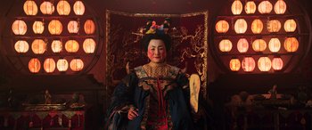 Movie still from “Mulan” (2020), directed by Niki Caro – A person in a costume sitting in a chair; Medium shot, Low angle
