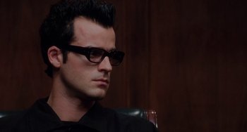 Movie still from “Mulholland Drive” (2001), directed by David Lynch – A man wearing glasses sitting in front of a wooden wall; Close Up shot, Low angle