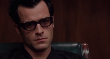 Movie still from “Mulholland Drive” (2001), directed by David Lynch – A person wearing glasses and a black shirt; Close Up shot, Over the shoulder angle