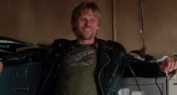 Movie still from “Mulholland Drive” (2001), directed by David Lynch – A man in a leather jacket smiling for the camera; Medium shot, High angle