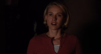 Movie still from “Mulholland Drive” (2001), directed by David Lynch – A woman in a red shirt is standing in a dark room; Close Up shot, Over the shoulder angle