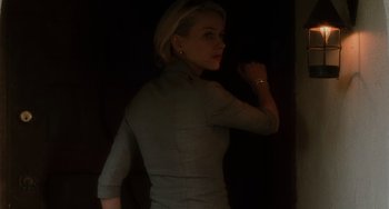 Movie still from “Mulholland Drive” (2001), directed by David Lynch – A woman standing in a dark room holding a cell phone; Medium shot, Low angle