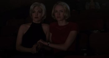 Movie still from “Mulholland Drive” (2001), directed by David Lynch – Two women sitting next to each other in a darkened room; Medium shot, Low angle