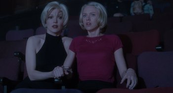 Movie still from “Mulholland Drive” (2001), directed by David Lynch – Two women are sitting in a movie theater holding remotes in their hands; Medium shot, Low angle