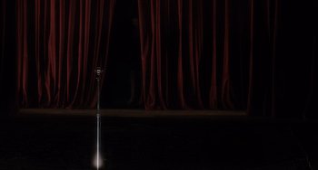 Movie still from “Mulholland Drive” (2001), directed by David Lynch – A microphone on a stage in front of a red curtain; Extreme Wide shot, High angle
