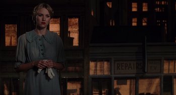 Movie still from “Mulholland Drive” (2001), directed by David Lynch – A woman standing in a dimly - lit room holding flowers; Medium shot, Over the shoulder angle