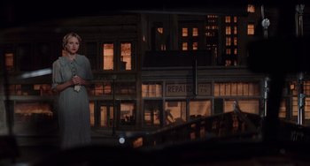 Movie still from “Mulholland Drive” (2001), directed by David Lynch – A woman standing in front of a building in the dark; Wide shot, Over the shoulder angle