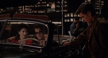 Movie still from “Mulholland Drive” (2001), directed by David Lynch – Two men in the back seat of a vintage car; Medium shot, High angle