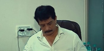Movie still from “Mumbai Mafia: Police vs the Underworld” (2023), directed by Raaghav Dar – A man sitting at a desk in front of a laptop; Close Up shot, High angle