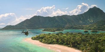 Movie still from “Murder Mystery 2” (2023), directed by Jeremy Garelick – An aerial view of a tropical island with a helicopter flying over it; Extreme Wide shot, High angle