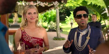 Movie still from “Murder Mystery 2” (2023), directed by Jeremy Garelick – A woman in a red dress standing next to a man in a suit; Medium shot, Over the shoulder angle