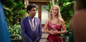 Movie still from “Murder Mystery 2” (2023), directed by Jeremy Garelick – A man and a woman standing next to each other holding a cell phone; Medium shot, Over the shoulder angle