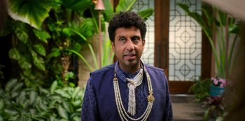 Movie still from “Murder Mystery 2” (2023), directed by Jeremy Garelick – A man in a blue jacket and a long necklace; Close Up shot, Low angle