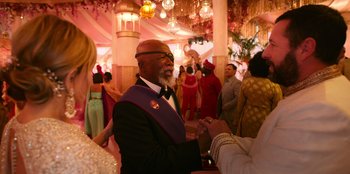 Movie still from “Murder Mystery 2” (2023), directed by Jeremy Garelick – An older man wearing a purple sash and a purple tie; Medium shot, Over the shoulder angle