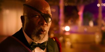 Movie still from “Murder Mystery 2” (2023), directed by Jeremy Garelick – An older man wearing a black eye patch; Close Up shot, Over the shoulder angle