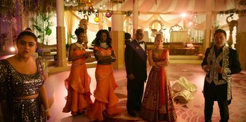 Movie still from “Murder Mystery 2” (2023), directed by Jeremy Garelick – A man and two women dressed up in orange; Wide shot, Low angle
