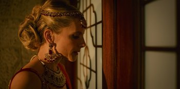 Movie still from “Murder Mystery 2” (2023), directed by Jeremy Garelick – A woman wearing a head piece and a necklace; Close Up shot, Over the shoulder angle