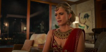 Movie still from “Murder Mystery 2” (2023), directed by Jeremy Garelick – A woman in a red and gold dress with a gold necklace; Close Up shot, Over the shoulder angle