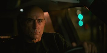 Movie still from “Murder Mystery 2” (2023), directed by Jeremy Garelick – A man sitting in the back seat of a car; Close Up shot, Over the shoulder angle