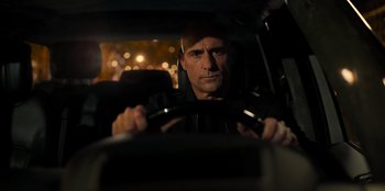 Movie still from “Murder Mystery 2” (2023), directed by Jeremy Garelick – A man driving a car at night in the dark; Close Up shot, Low angle
