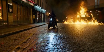 Movie still from “Murder Mystery 2” (2023), directed by Jeremy Garelick – A person riding a motorcycle down a street at night; Extreme Wide shot, High angle