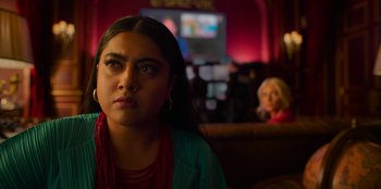 Movie still from “Murder Mystery 2” (2023), directed by Jeremy Garelick – A woman sitting in front of another woman in front of a television; Close Up shot, Over the shoulder angle