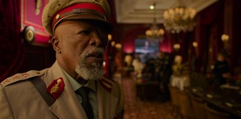 Movie still from “Murder Mystery 2” (2023), directed by Jeremy Garelick – An older man wearing a military uniform in a room; Close Up shot, Over the shoulder angle