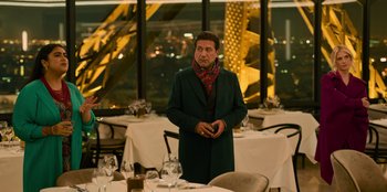 Movie still from “Murder Mystery 2” (2023), directed by Jeremy Garelick – A man standing in front of a dining room table; Medium shot, Over the shoulder angle