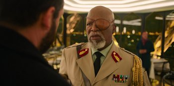 Movie still from “Murder Mystery 2” (2023), directed by Jeremy Garelick – An older man in a military uniform talking to another man; Close Up shot, Over the shoulder angle