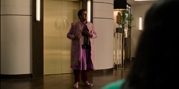 Movie still from “Murder Mystery 2” (2023), directed by Jeremy Garelick – A person standing in a room holding a camera; Medium shot, Over the shoulder angle