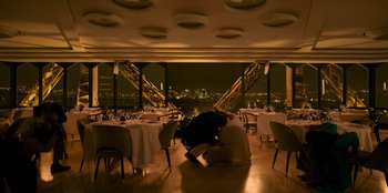 Movie still from “Murder Mystery 2” (2023), directed by Jeremy Garelick – Two people are sitting in a restaurant with a view of the city; Extreme Wide shot, High angle