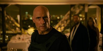 Movie still from “Murder Mystery 2” (2023), directed by Jeremy Garelick – A man with bald head wearing a black shirt; Close Up shot, Low angle