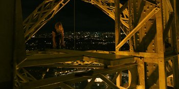Movie still from “Murder Mystery 2” (2023), directed by Jeremy Garelick – A woman standing on top of a metal structure at night; Wide shot, High angle
