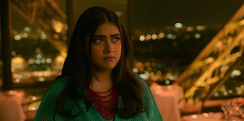 Movie still from “Murder Mystery 2” (2023), directed by Jeremy Garelick – A woman with long black hair wearing a green shirt; Close Up shot, Over the shoulder angle