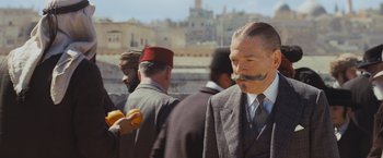 Movie still from “Murder on the Orient Express” (2017), directed by Kenneth Branagh – A man with a fake mustache on his face; Medium shot, Over the shoulder angle