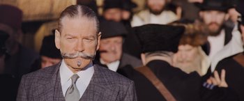 Movie still from “Murder on the Orient Express” (2017), directed by Kenneth Branagh – A man that is wearing a suit and a mustache; Close Up shot, Over the shoulder angle