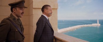 Movie still from “Murder on the Orient Express” (2017), directed by Kenneth Branagh – A man in a suit standing on a balcony; Medium shot, Over the shoulder angle