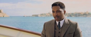 Movie still from “Murder on the Orient Express” (2017), directed by Kenneth Branagh – A man wearing a suit and tie standing in front of a body of water; Close Up shot, Over the shoulder angle