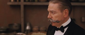 Movie still from “Murder on the Orient Express” (2017), directed by Kenneth Branagh – A person wearing a suit and tie; Close Up shot, Low angle