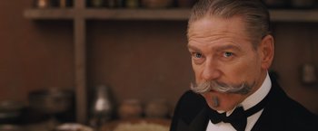 Movie still from “Murder on the Orient Express” (2017), directed by Kenneth Branagh – An older man in a tuxedo with a long mustache; Close Up shot, Low angle