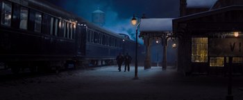 Movie still from “Murder on the Orient Express” (2017), directed by Kenneth Branagh – Two people standing in front of a train at night; Extreme Wide shot, High angle