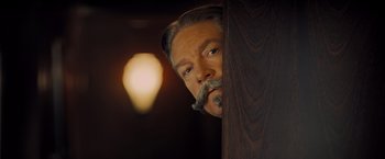 Movie still from “Murder on the Orient Express” (2017), directed by Kenneth Branagh – A man with a beard and a mustache is leaning against a wall; Close Up shot, Low angle