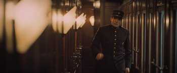 Movie still from “Murder on the Orient Express” (2017), directed by Kenneth Branagh – A man in a uniform standing next to a wall; Medium shot, Low angle