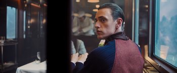 Movie still from “Murder on the Orient Express” (2017), directed by Kenneth Branagh – A young man looking into a mirror in a restaurant; Medium shot, Over the shoulder angle