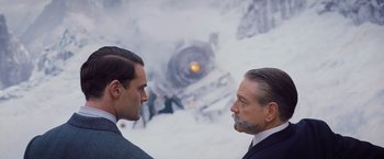 Movie still from “Murder on the Orient Express” (2017), directed by Kenneth Branagh – Two men in business suits standing next to each other; Close Up shot, Over the shoulder angle