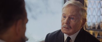 Movie still from “Murder on the Orient Express” (2017), directed by Kenneth Branagh – An older man wearing a suit and tie; Close Up shot, Over the shoulder angle